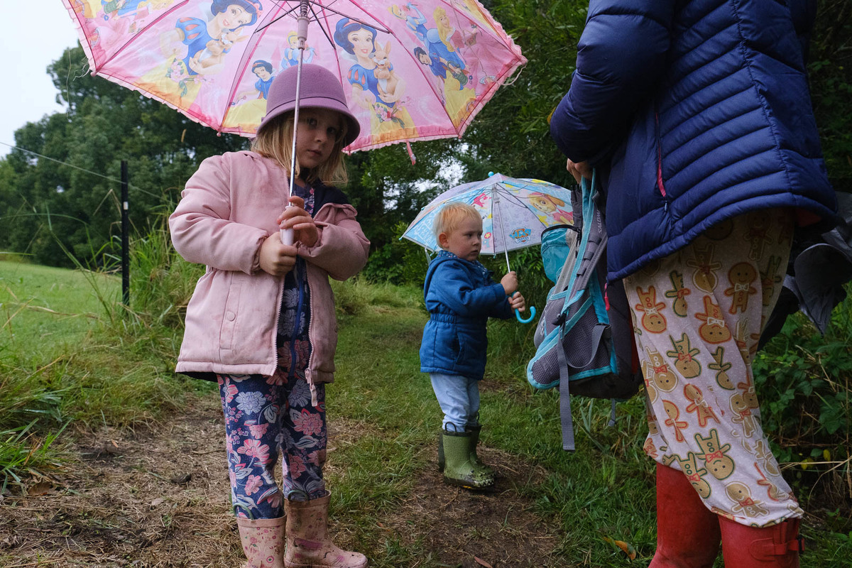 Children in pyjamas in the rain with umbrellas