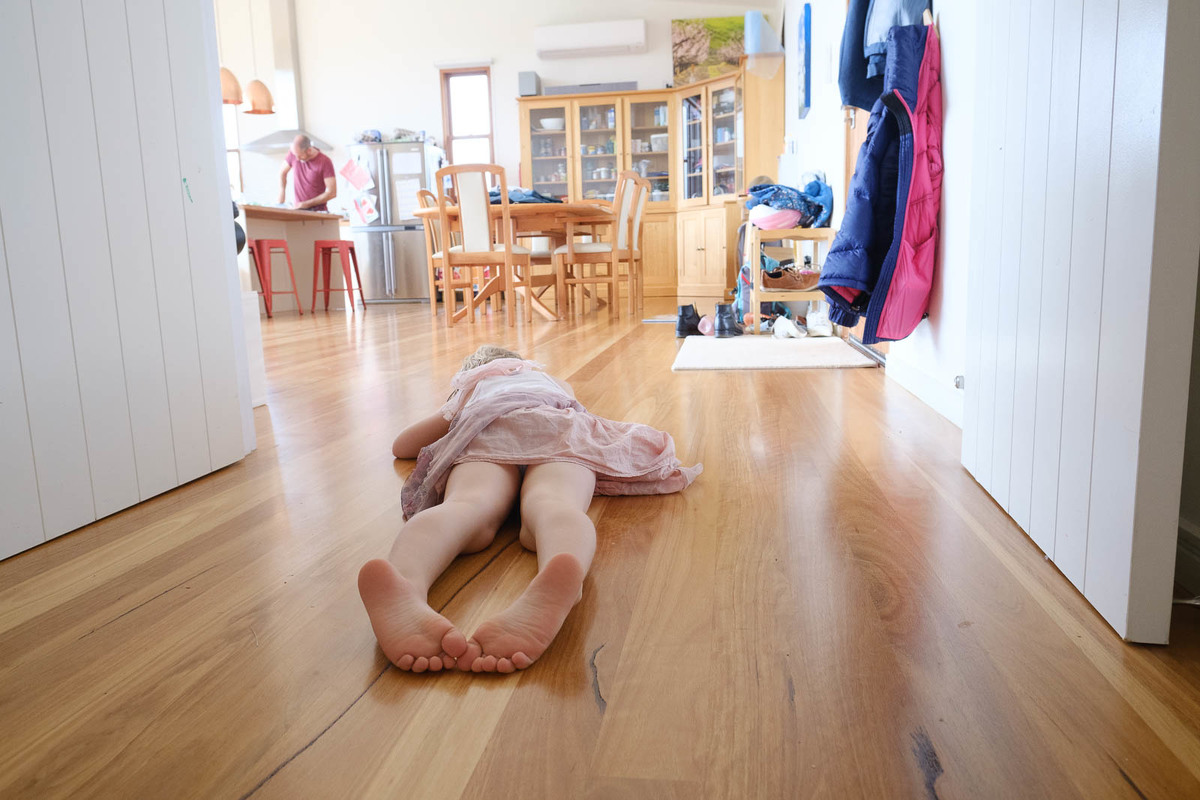 Young girl lying flat out on the hallway floor